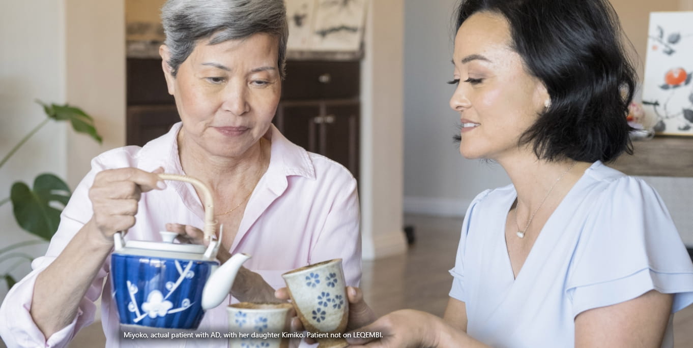 Mother pouring tea for adult daughter sitting at table